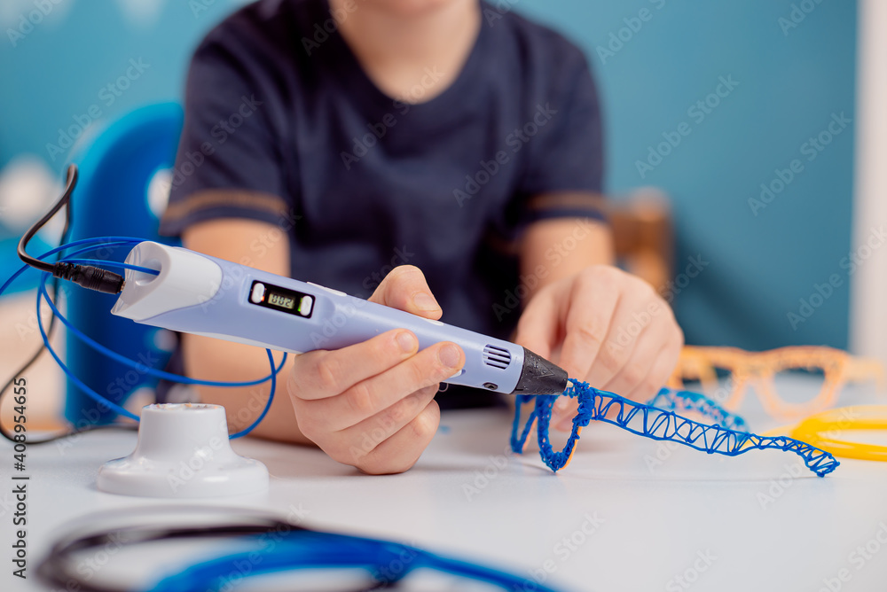 Focused child with 3d printing pen creating a toy